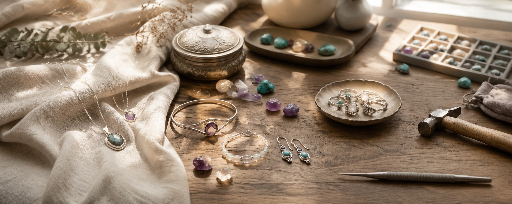 Natural gemstone jewelry arranged across a warm artisan workbench